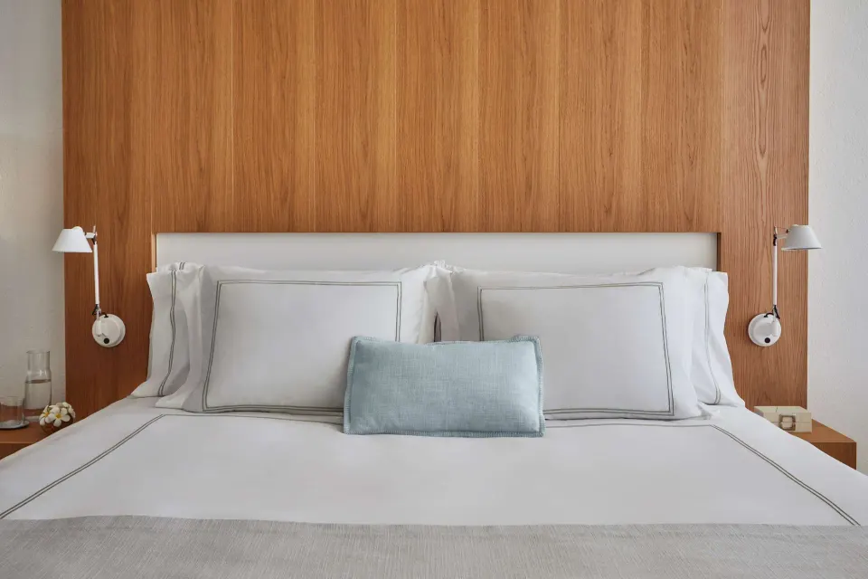 King bed with white linens and wood headboard in a Resort View room at Viceroy Los Cabos.