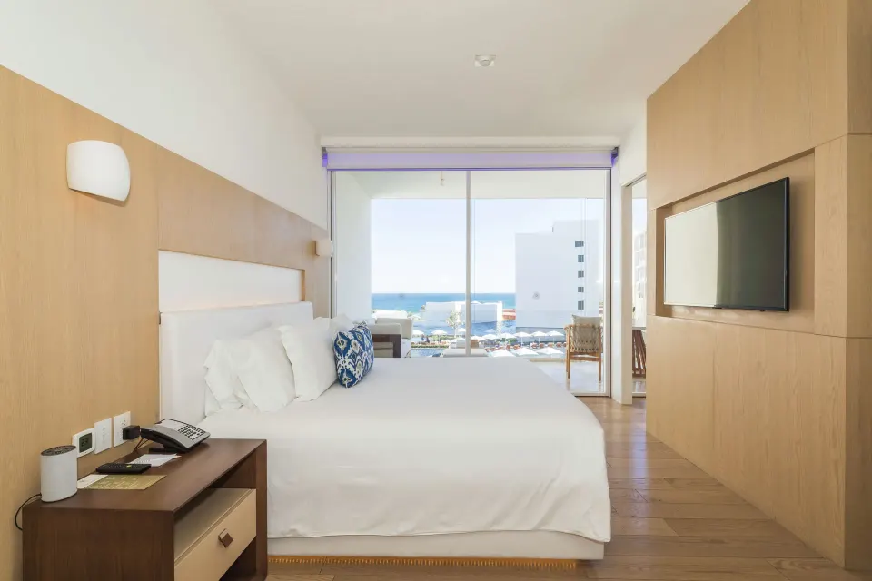 One Bedroom Partial Ocean View suite bed with TV wall and balcony view at Viceroy Los Cabos.