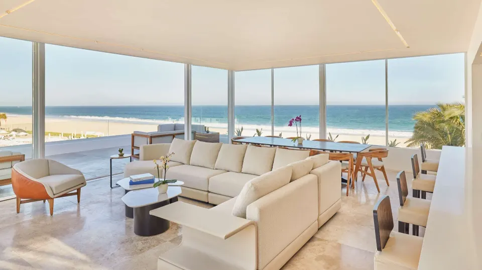 Bright suite lounge with sectional sofa, dining table, and ocean view at Viceroy Los Cabos.