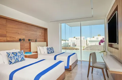 Double-bed guest room with desk, wall TV, and water view at Viceroy Los Cabos.