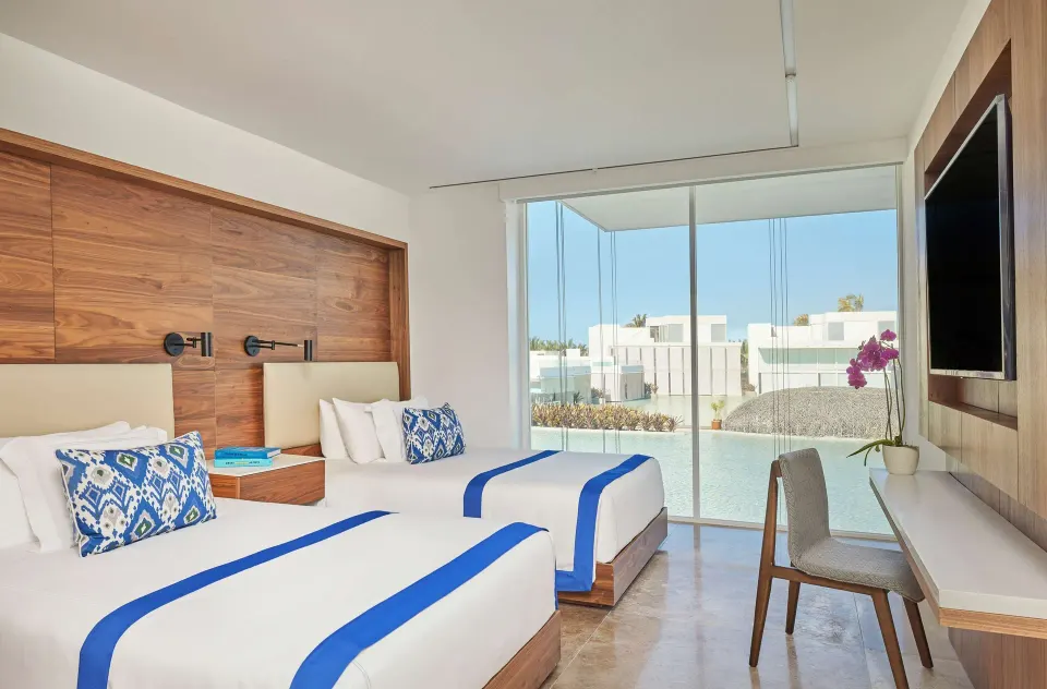 Double-bed guest room with desk, wall TV, and water view at Viceroy Los Cabos.