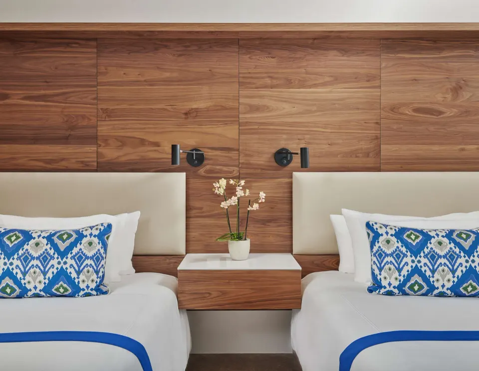 Two double beds with patterned pillows and a shared nightstand at Viceroy Los Cabos.