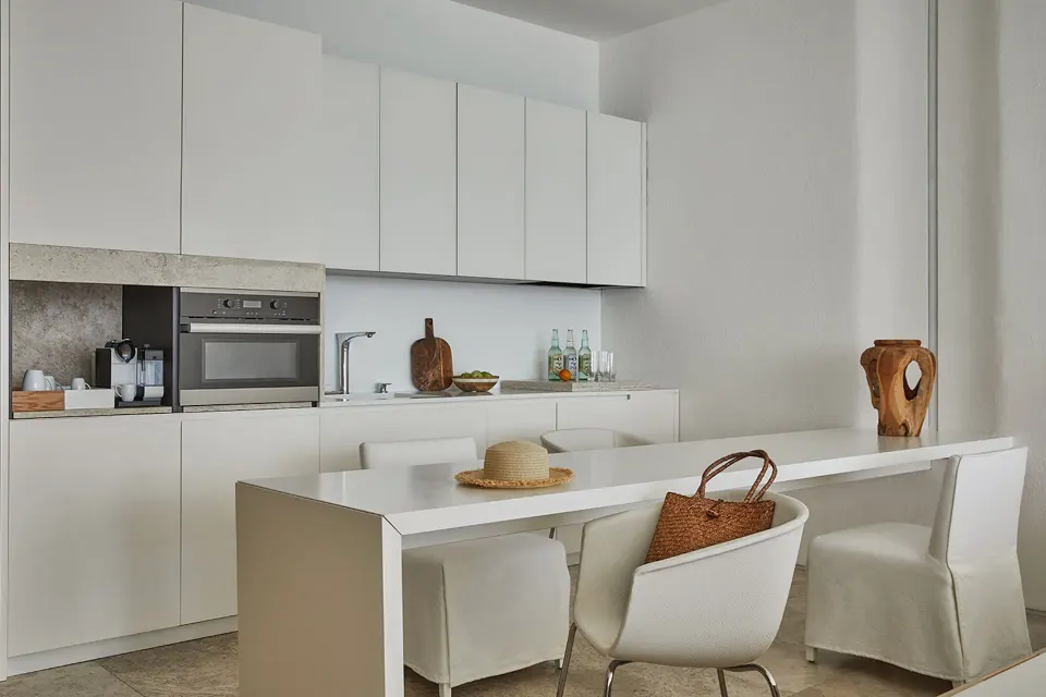 Suite kitchenette and dining table with white cabinetry at Viceroy Los Cabos.