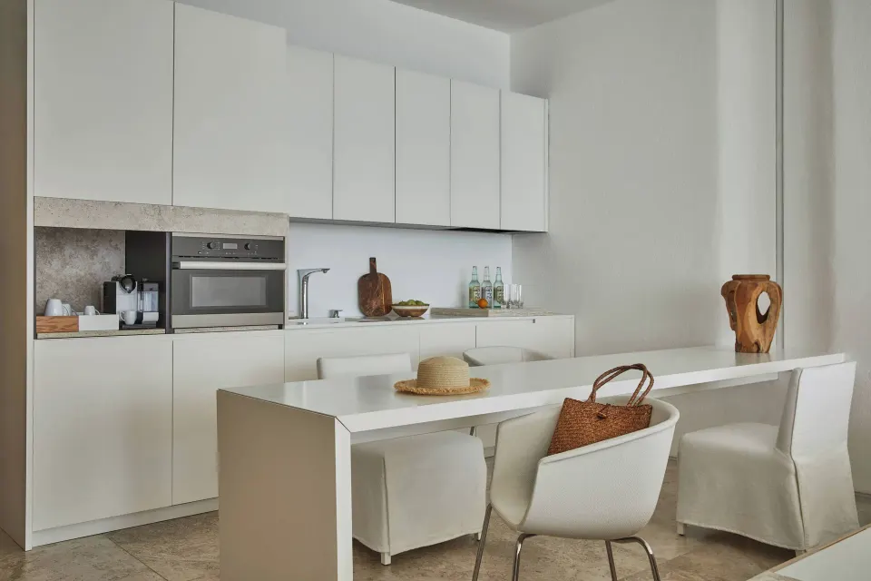 White suite kitchen and dining table with chairs and woven bag at Viceroy Los Cabos.