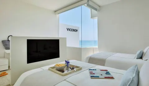 Twin-bed room with TV partition and ocean-facing window at Viceroy Los Cabos.