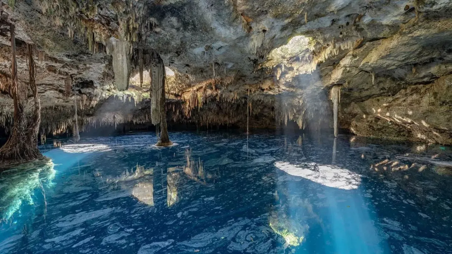 Blue cenote water inside a limestone cave near Viceroy Riviera Maya.