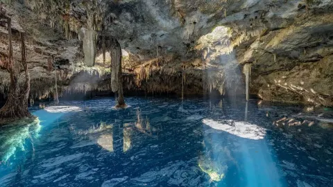 Blue cenote water inside a limestone cave near Viceroy Riviera Maya.