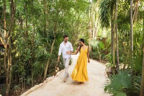 Couple walking on a lush garden path at Viceroy Riviera Maya.