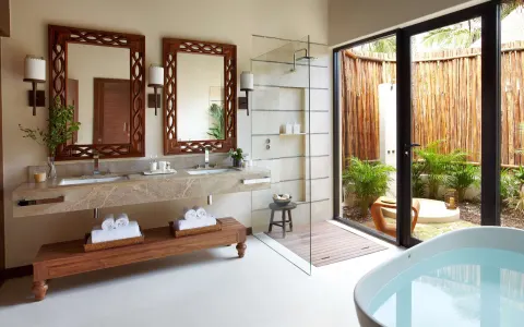 Premium Villa bathroom with double vanity, glass shower, tub, and garden view at Viceroy Riviera Maya.