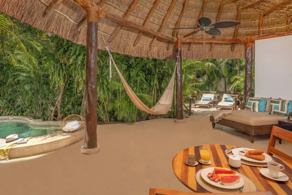 Royal Villa palapa terrace with hammock, breakfast table, and pool at Viceroy Riviera Maya.