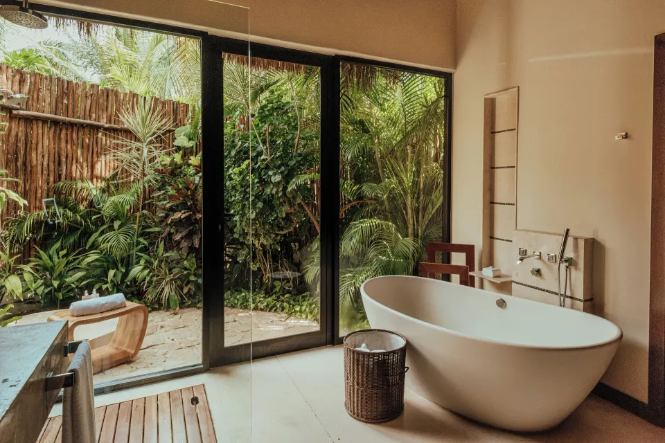 Villa bathroom with freestanding tub and garden view at Viceroy Riviera Maya.