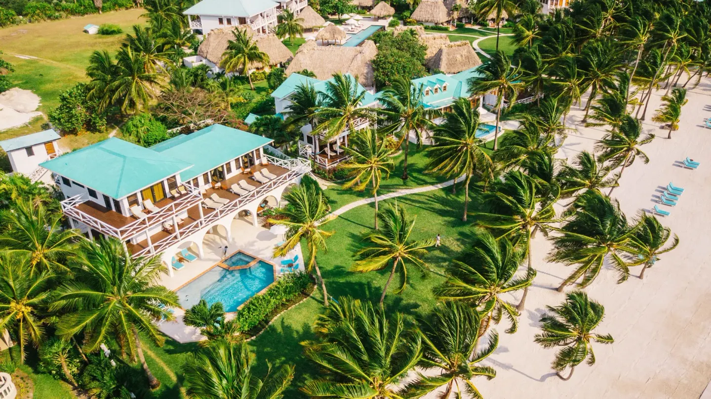Aerial view of resort buildings, pool, beach, and palms at Victoria House Resort & Spa.