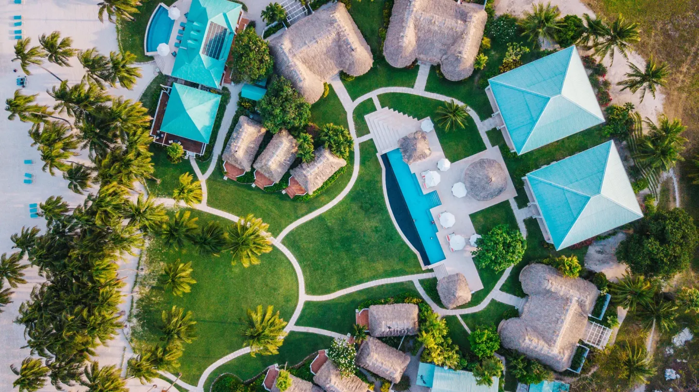 Aerial view of pools, paths, palms, and thatched roofs at Victoria House Resort & Spa.