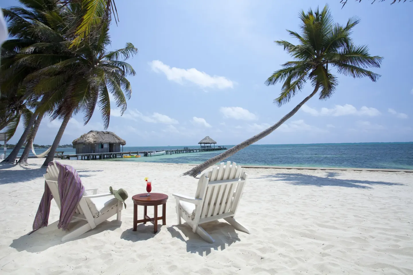 Beach chairs, cocktail table, palms, and pier at Victoria House Resort & Spa.