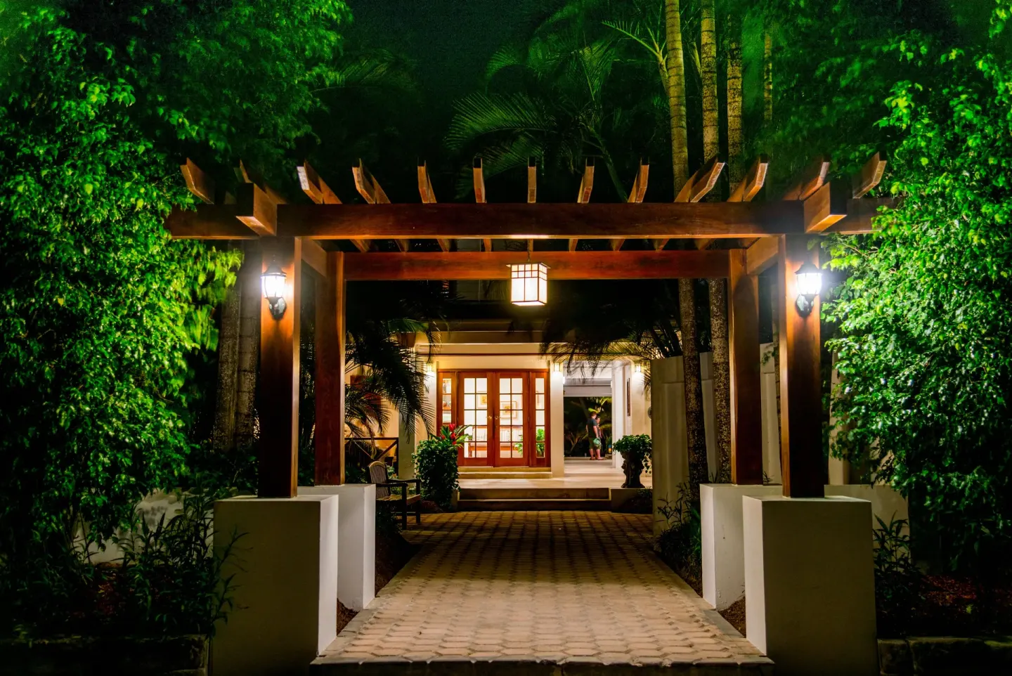 Lit garden entrance with wooden pergola at night at Victoria House Resort & Spa.