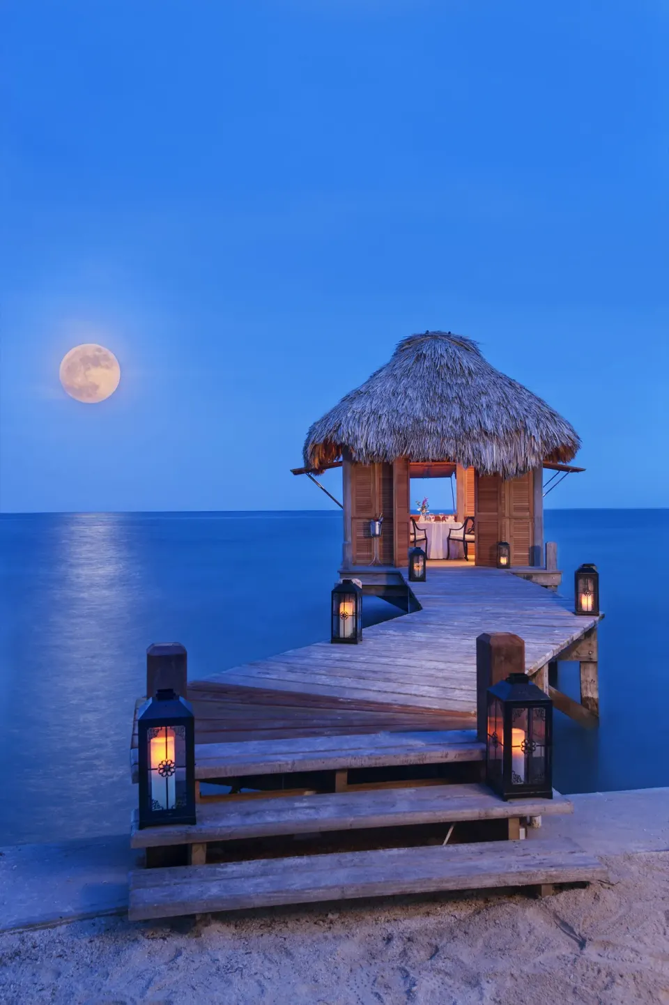Lantern-lit dock and thatched overwater palapa at Victoria House Resort & Spa.