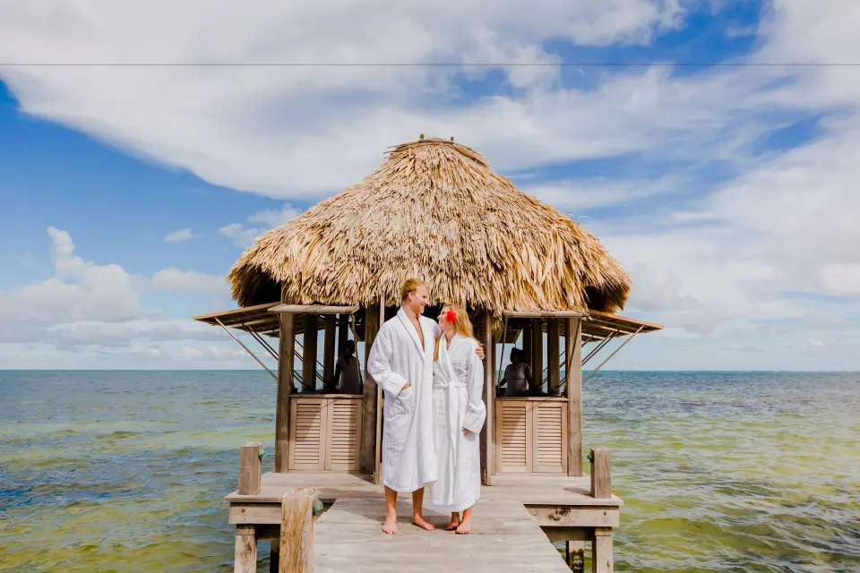 Couple in white robes on an overwater palapa dock at Victoria House Resort & Spa.