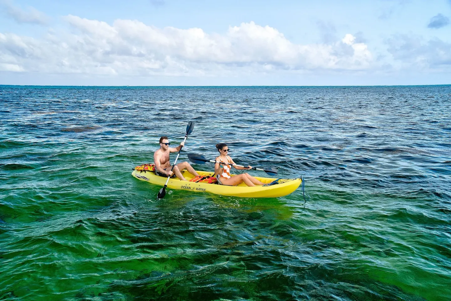 Two guests paddle a yellow kayak on the sea near Victoria House Resort & Spa.