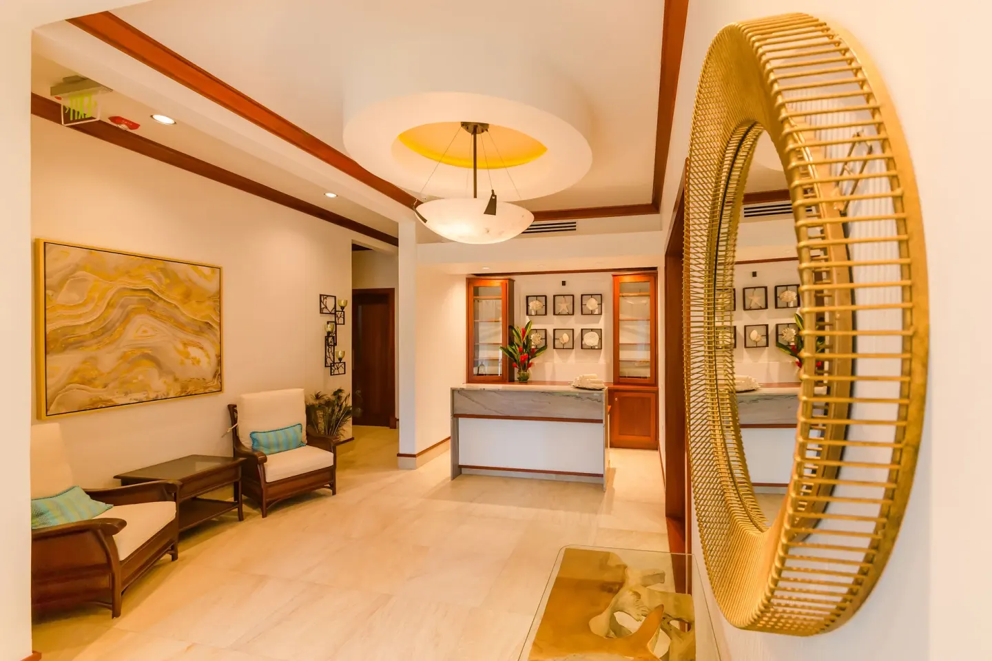 Spa reception lounge with chairs and a round wall mirror at Victoria House Resort & Spa.