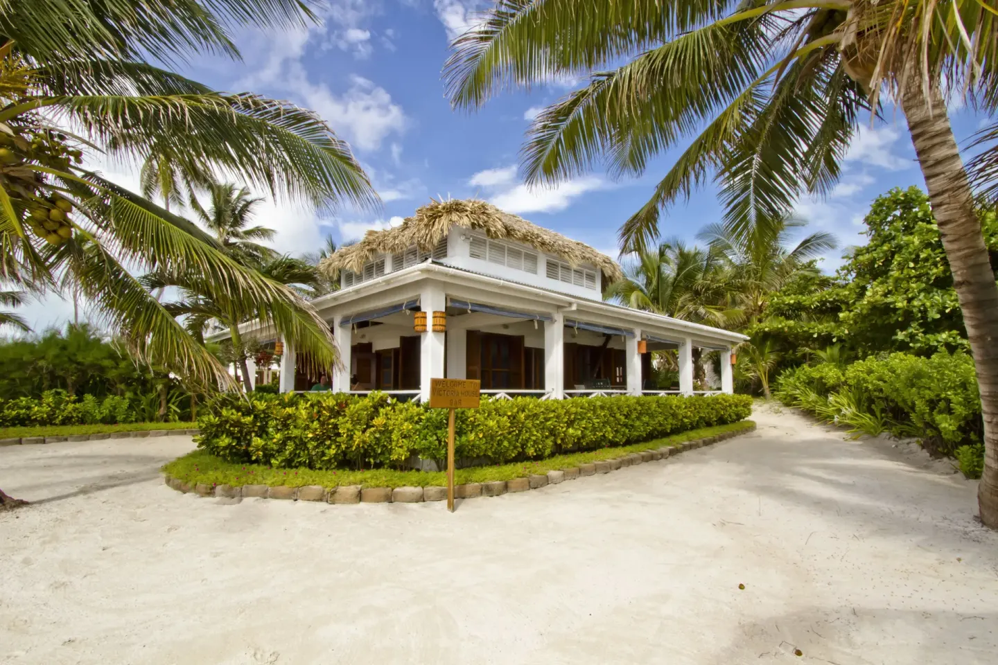 Thatched-roof building among palms and sandy paths at Victoria House Resort & Spa.