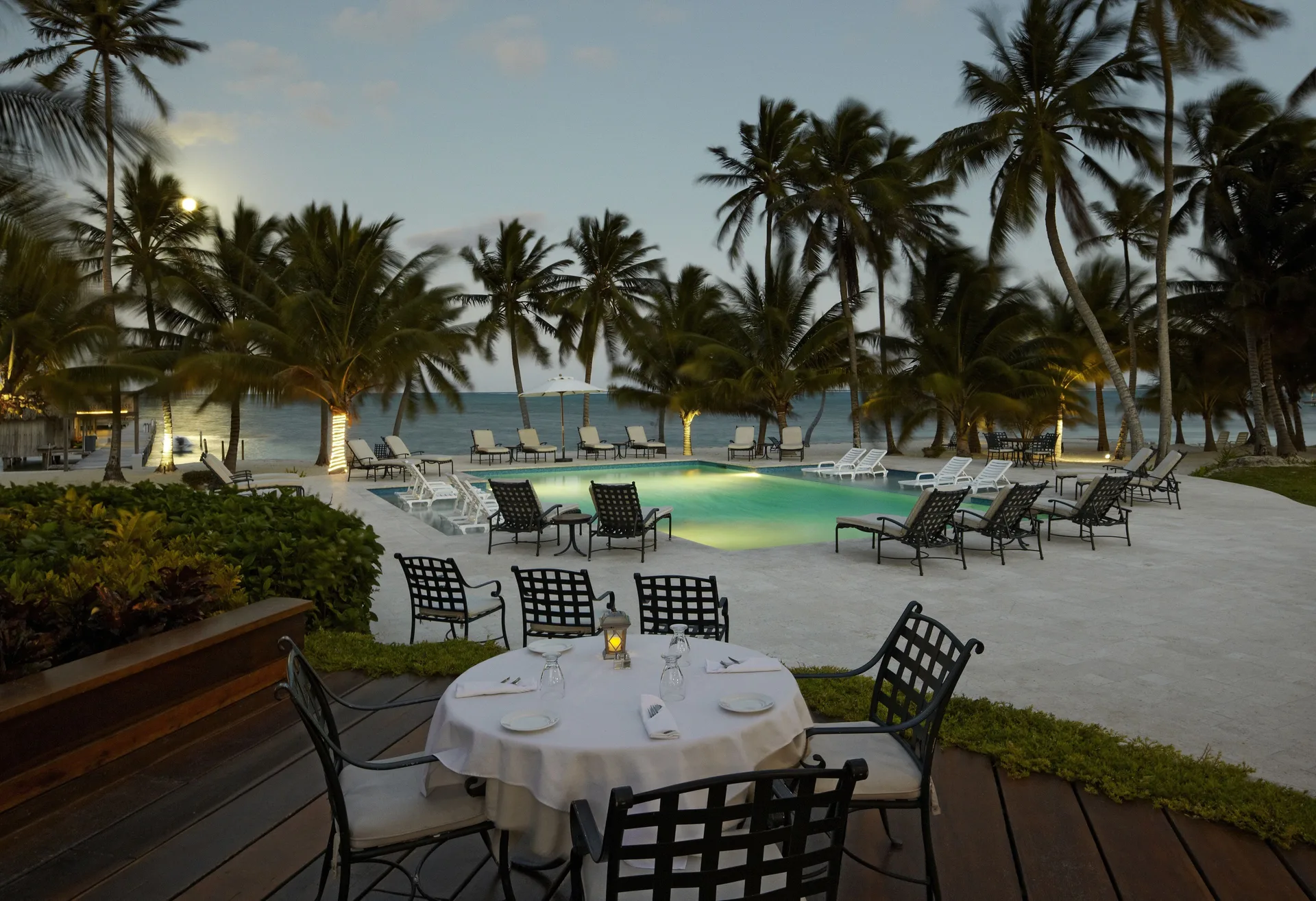 Poolside dining table and lounge chairs by the sea at Victoria House Resort & Spa.