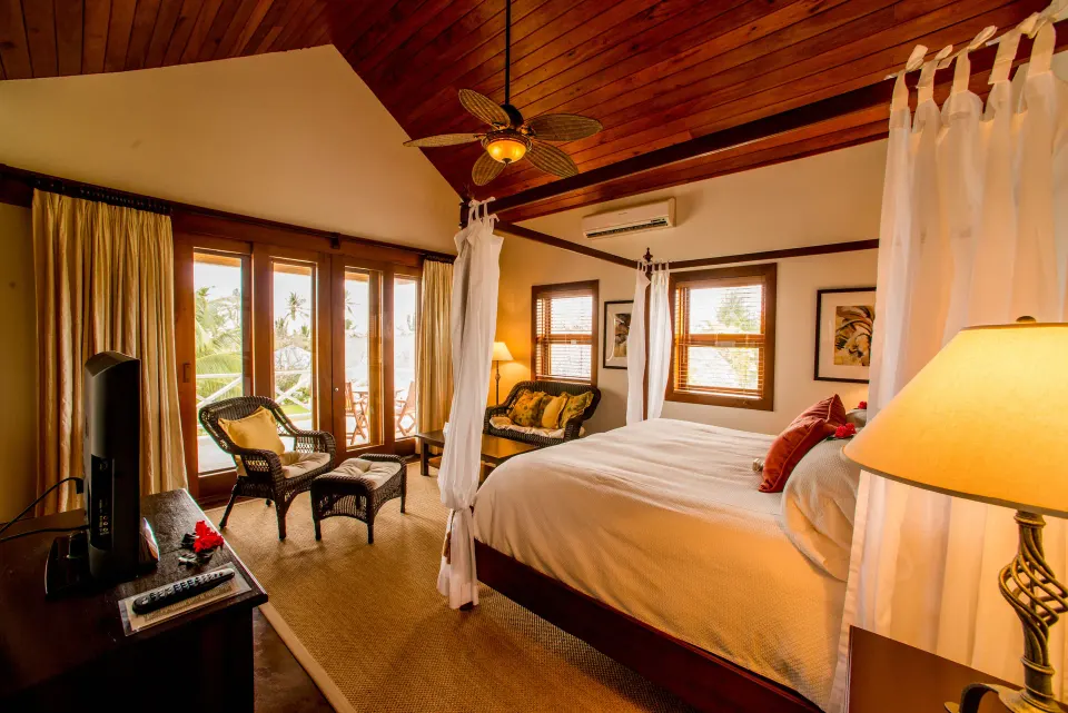 One Bedroom Infinity Suite four-poster bed and seating area at Victoria House Resort & Spa.