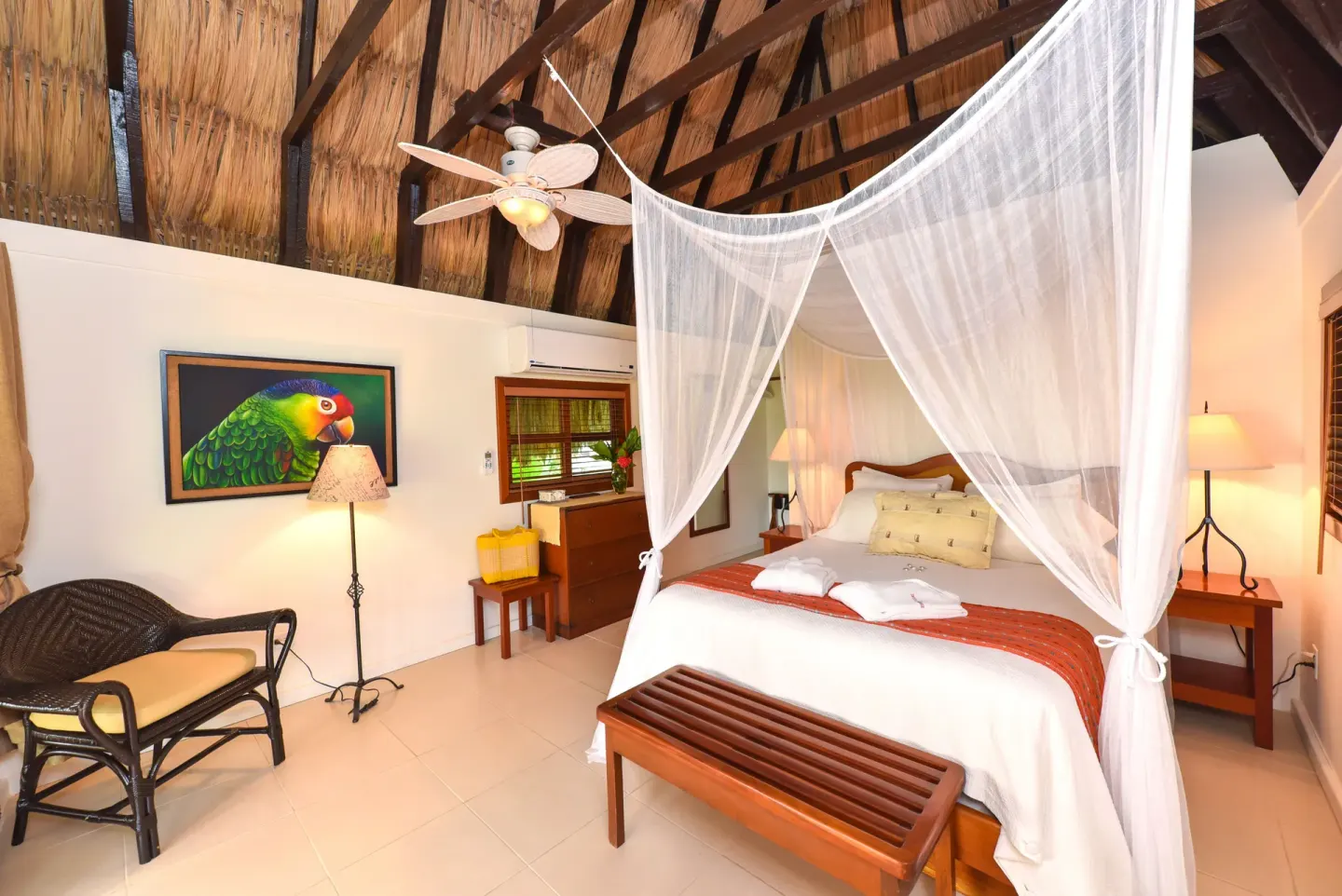 Casita king bed with mosquito net and thatched ceiling at Victoria House Resort & Spa.