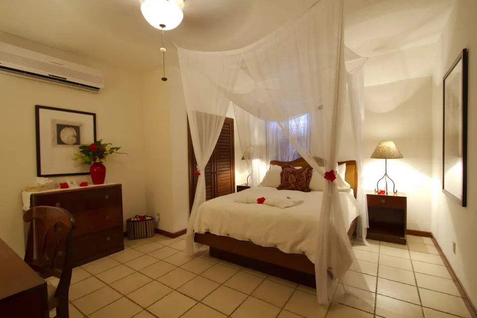 Stateroom bedroom with a canopied bed and wood furnishings at Victoria House Resort & Spa.