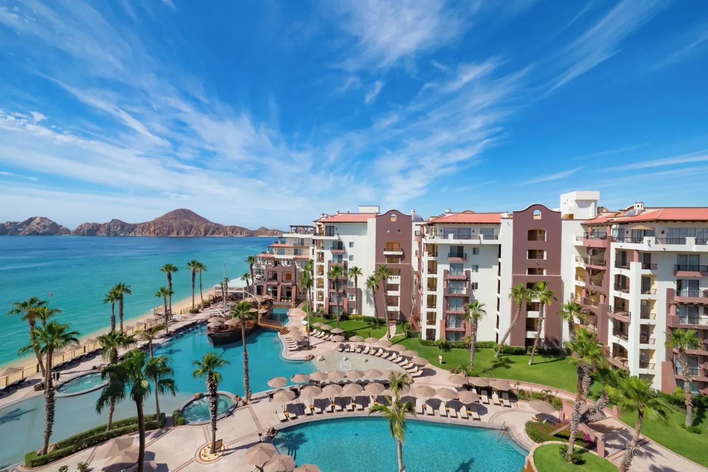 Aerial view of pools, beachfront buildings, and ocean at Villa del Arco Beach Resort & Spa Cabo San Lucas.