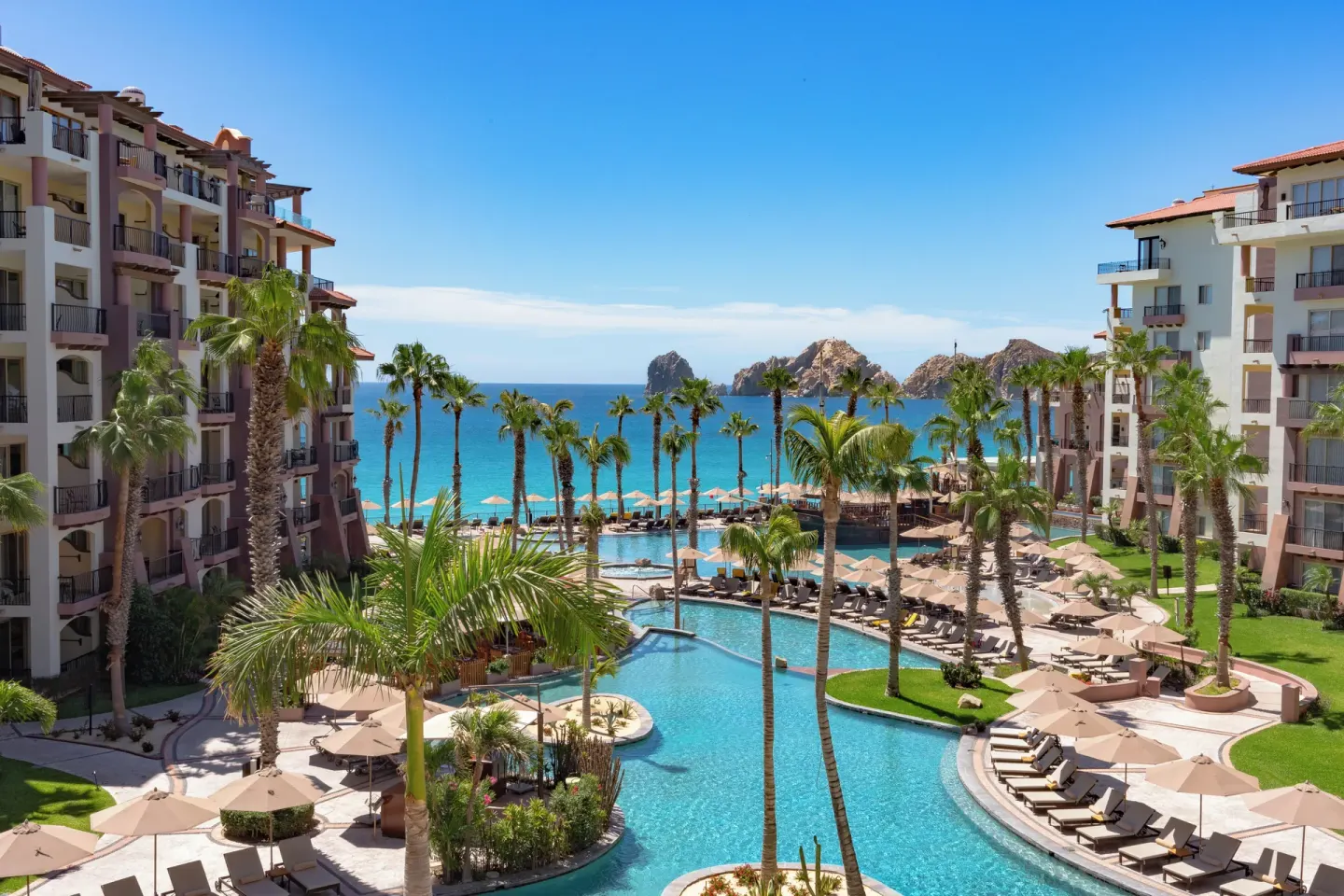 Central pool courtyard with ocean and rock formations at Villa del Arco Beach Resort & Spa Cabo San Lucas.
