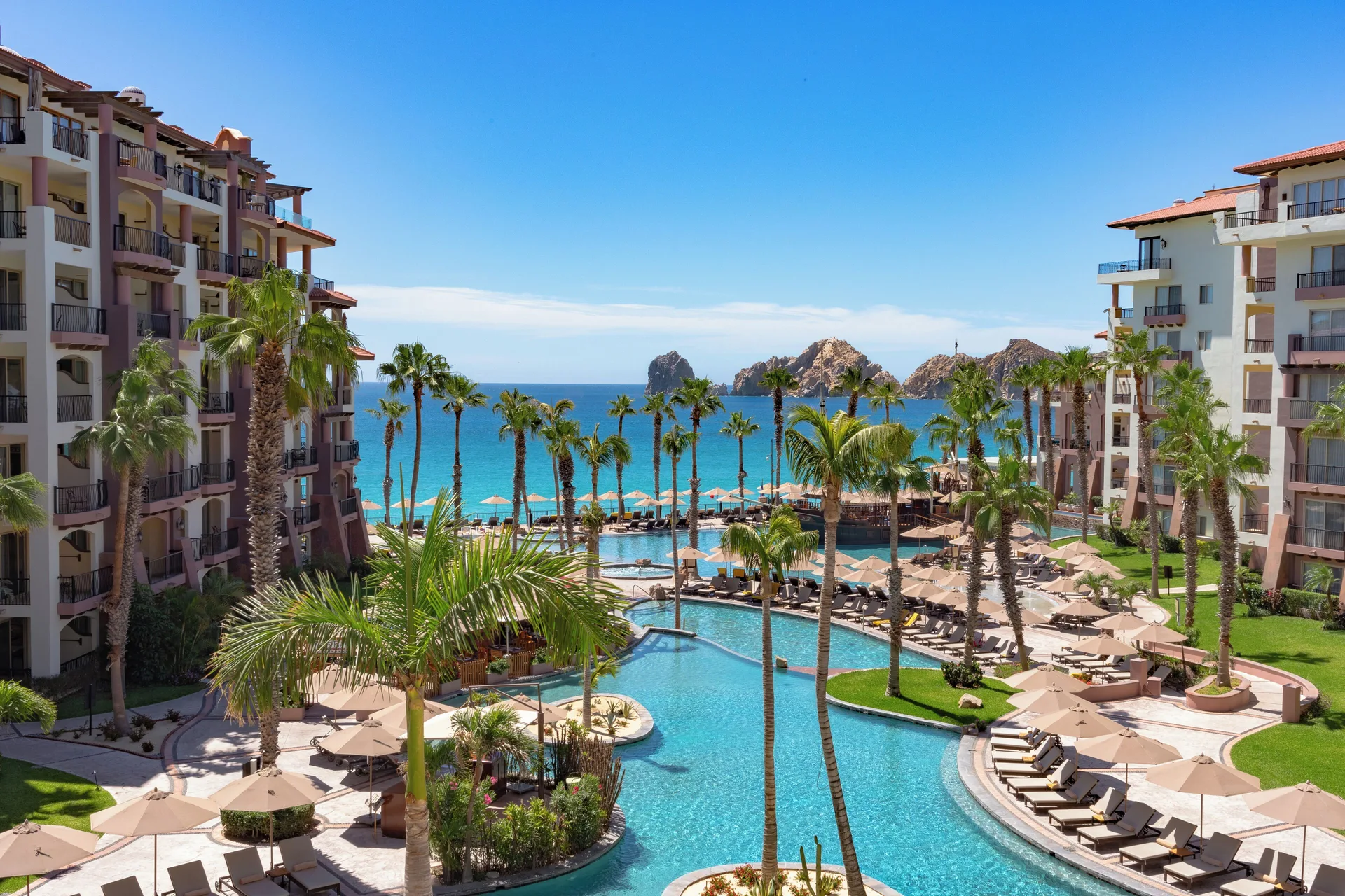 Central pool courtyard with ocean and rock formations at Villa del Arco Beach Resort & Spa Cabo San Lucas.