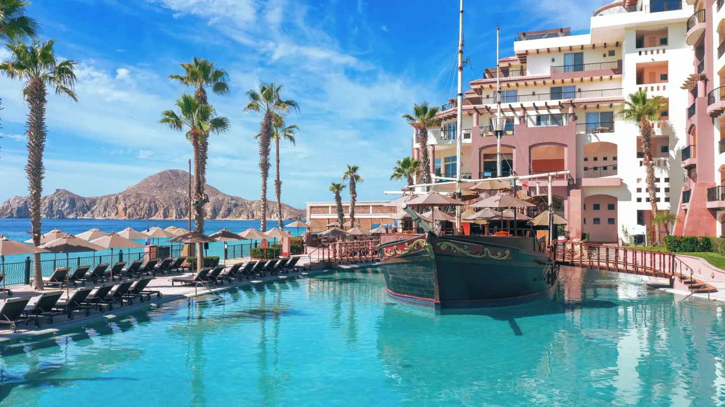 Main pool, ship feature, lounge chairs, and ocean backdrop at Villa del Arco Beach Resort & Spa Cabo San Lucas.