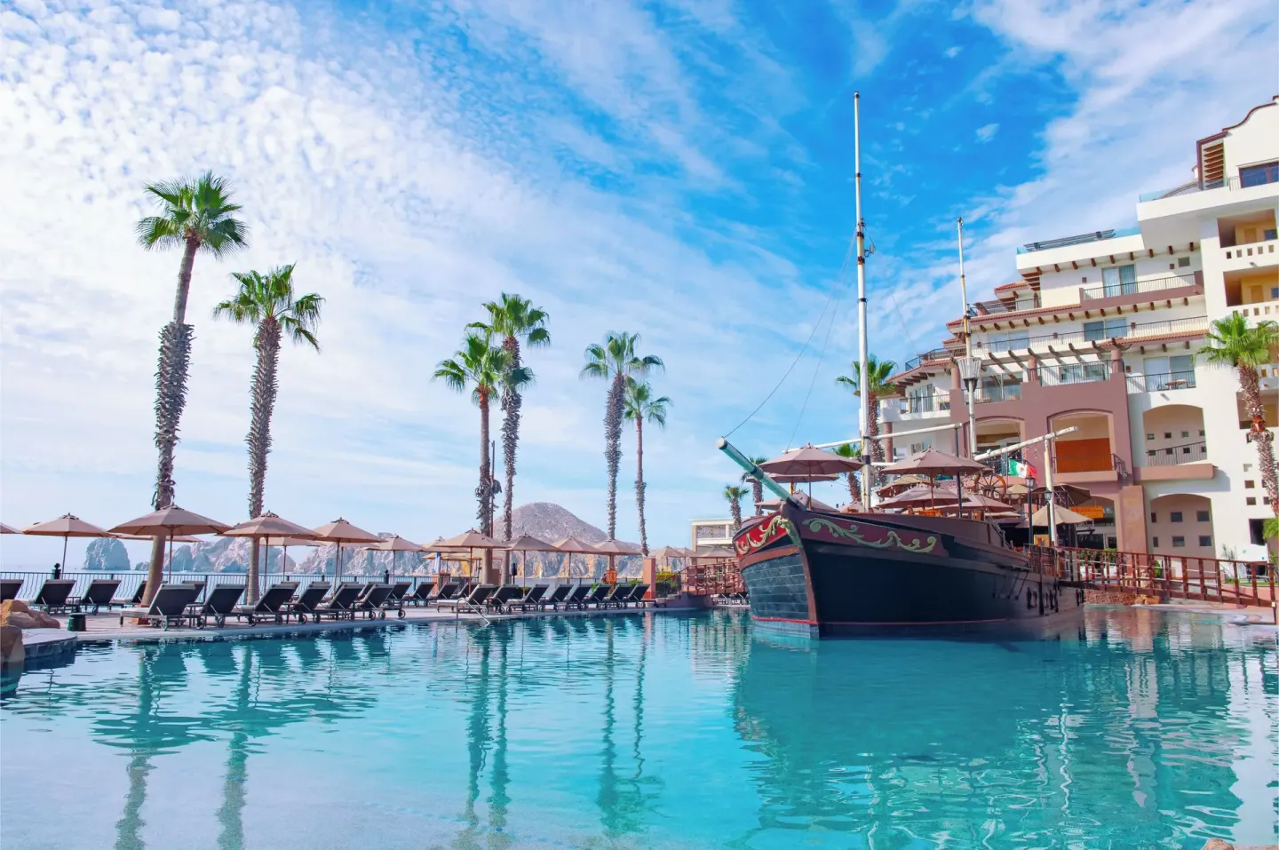 Poolside ship feature and lounge chairs at Villa del Arco Beach Resort & Spa Cabo San Lucas.