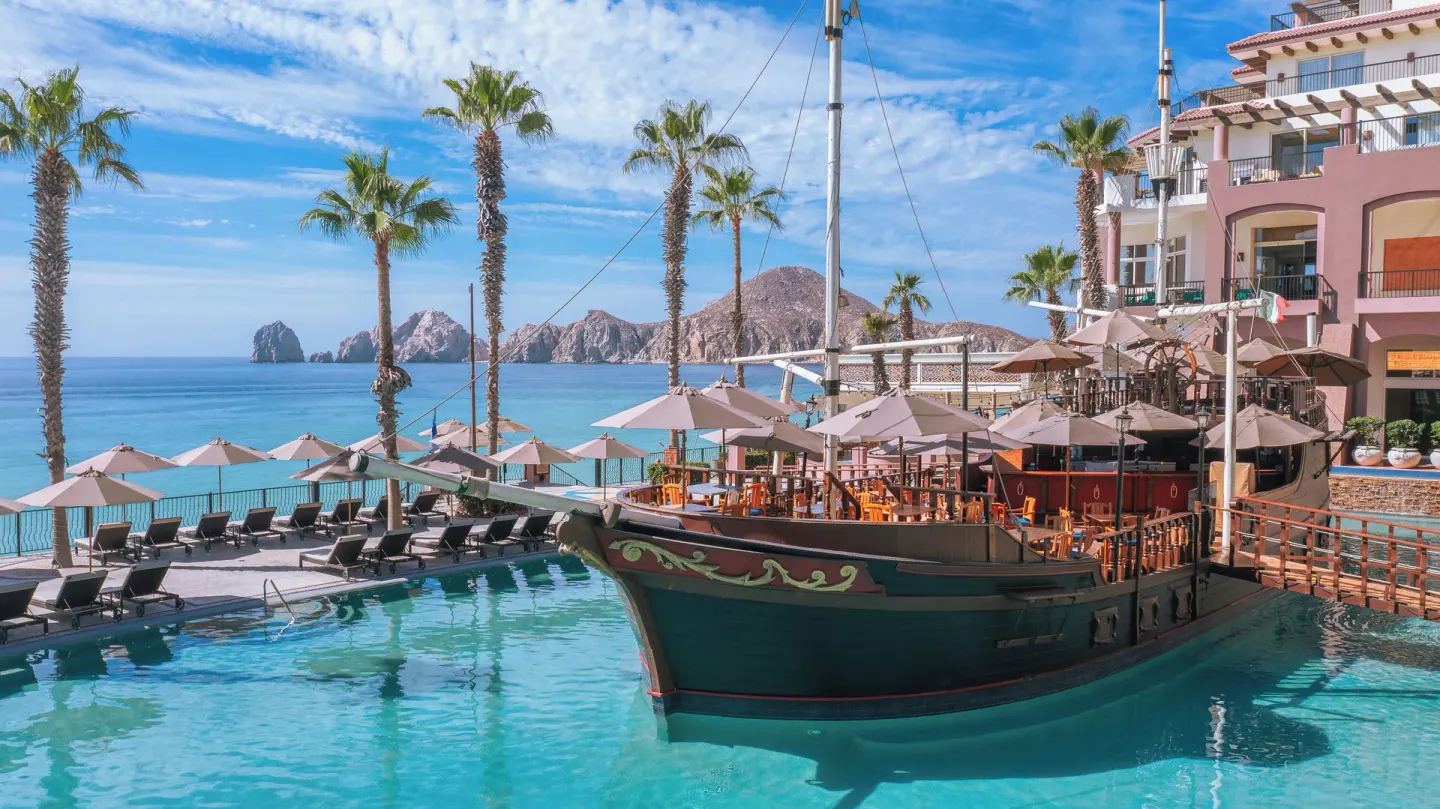 Ship-shaped pool feature with umbrellas and ocean view at Villa del Arco Beach Resort & Spa Cabo San Lucas.