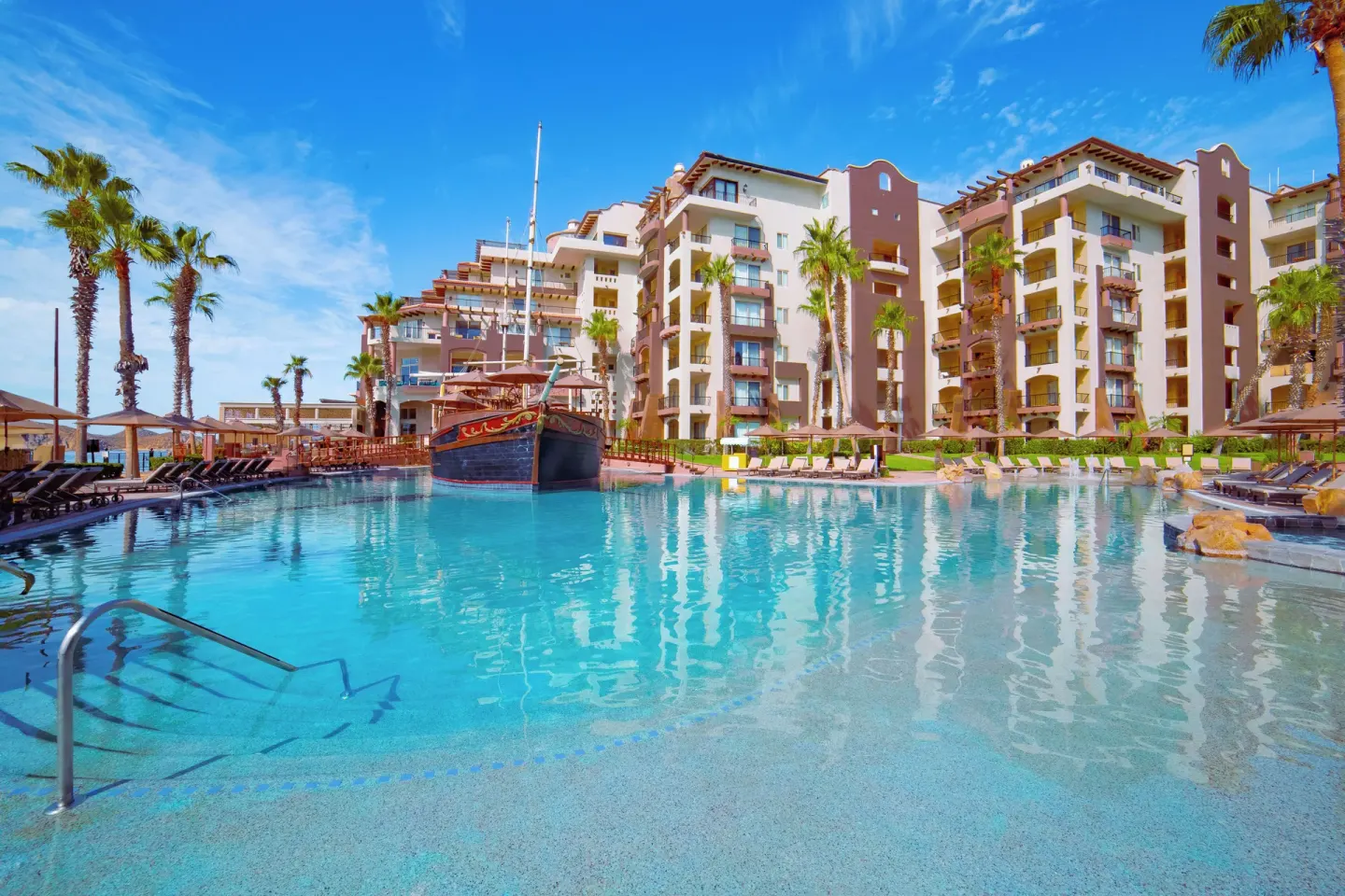 Wide main pool view with resort buildings and ship feature at Villa del Arco Beach Resort & Spa Cabo San Lucas.