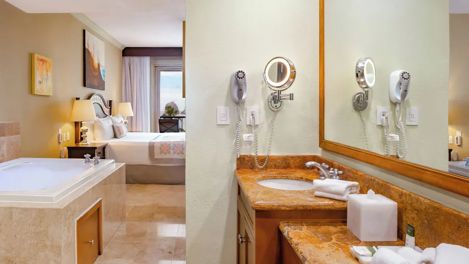 Two Bedroom Suite sink, soaking tub, and bedroom at Villa del Arco Beach Resort & Spa Cabo San Lucas.