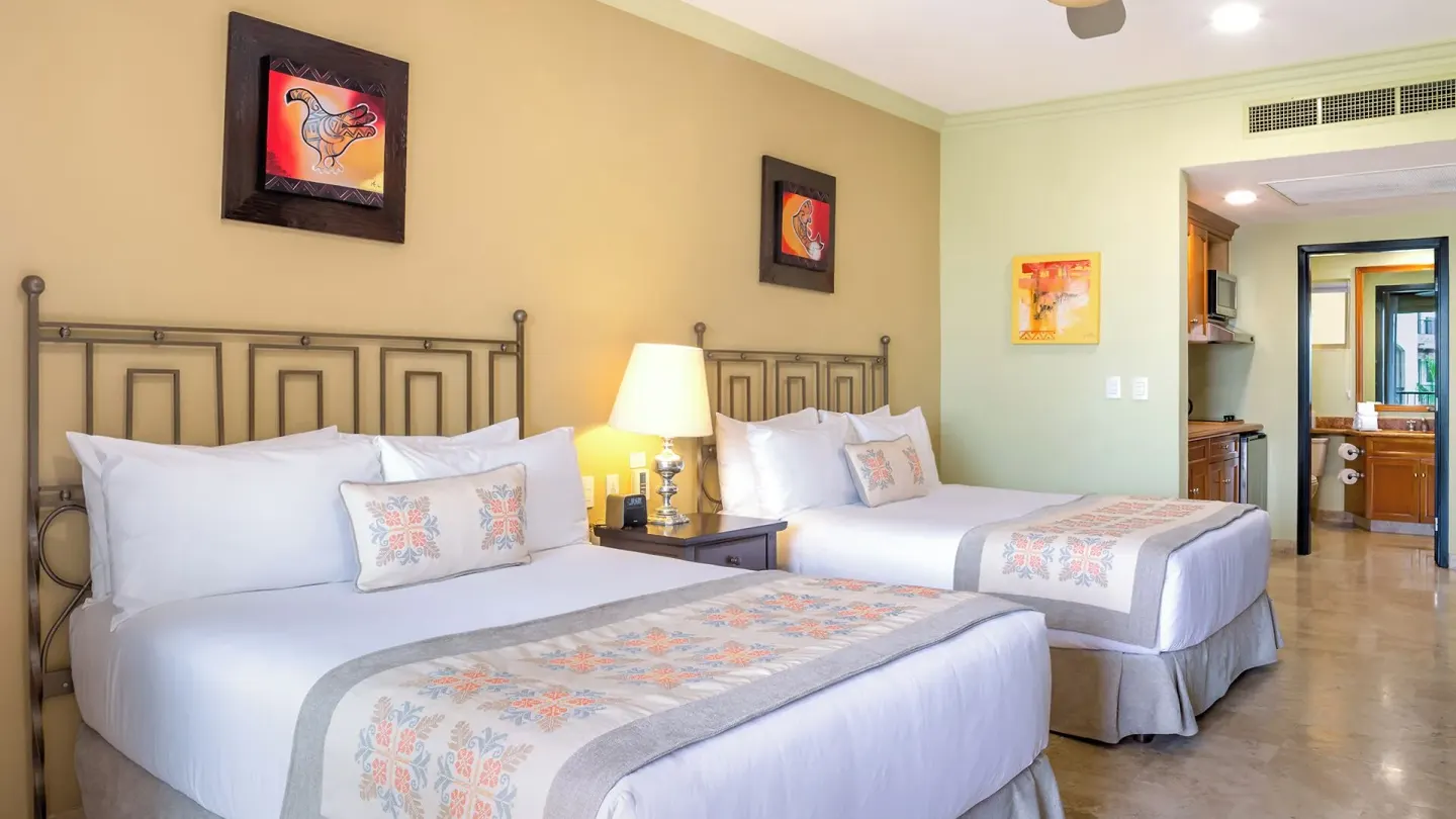 Two Bedroom Suite with two beds and bathroom doorway at Villa del Arco Beach Resort & Spa Cabo San Lucas.