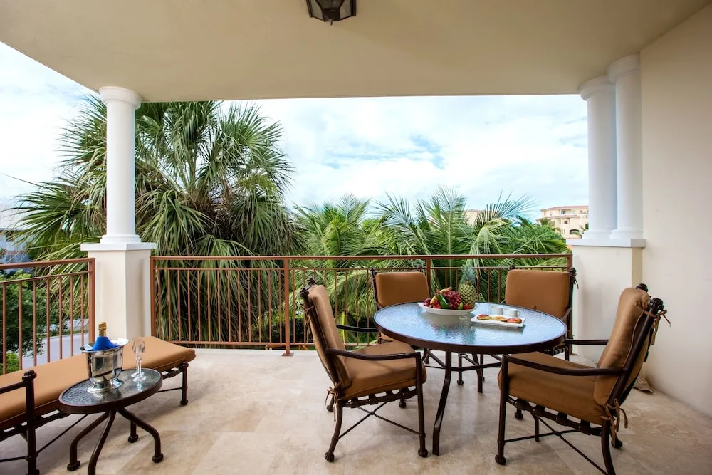 Spacious balcony with cushioned dining chairs and palm views at Villa del Mar.