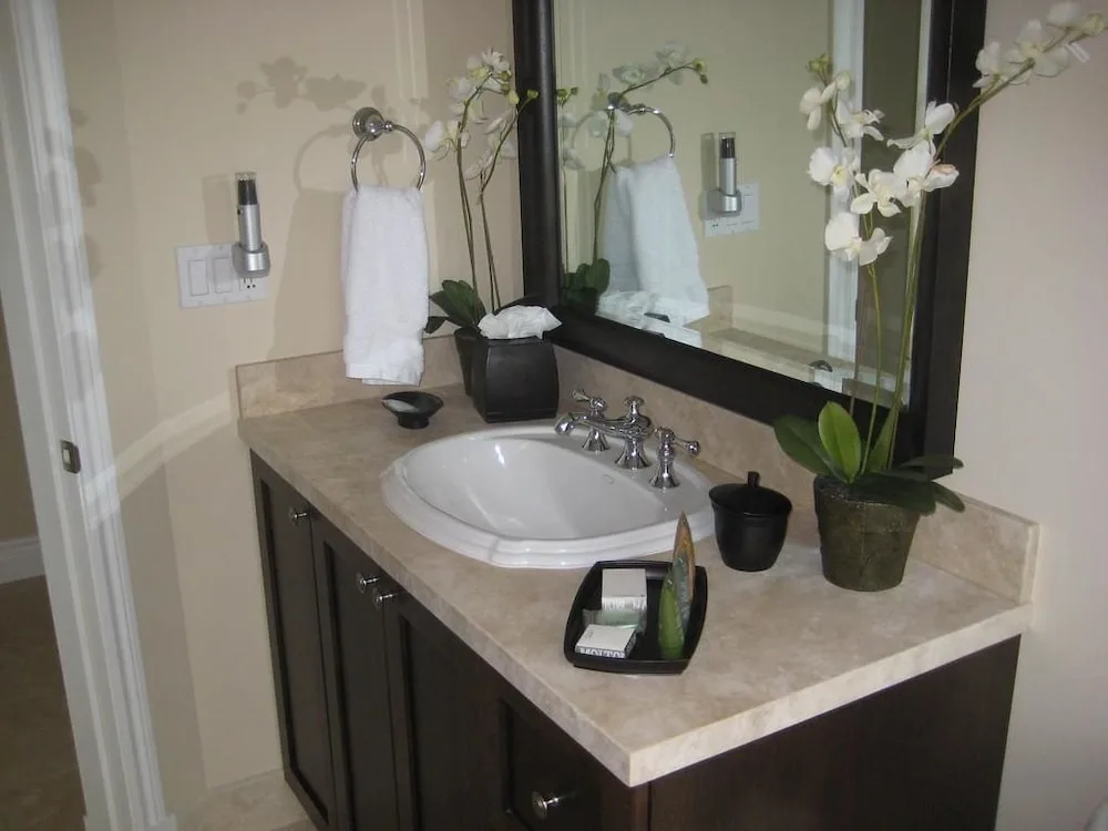 Bathroom vanity with a framed mirror, sink, towels, and orchids at Villa del Mar.