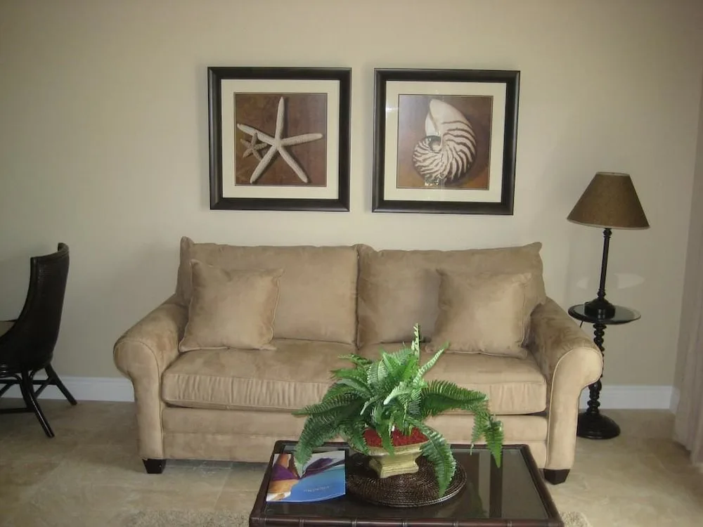 Beige sitting area with sofa, shell artwork and coffee table plant at Villa del Mar.