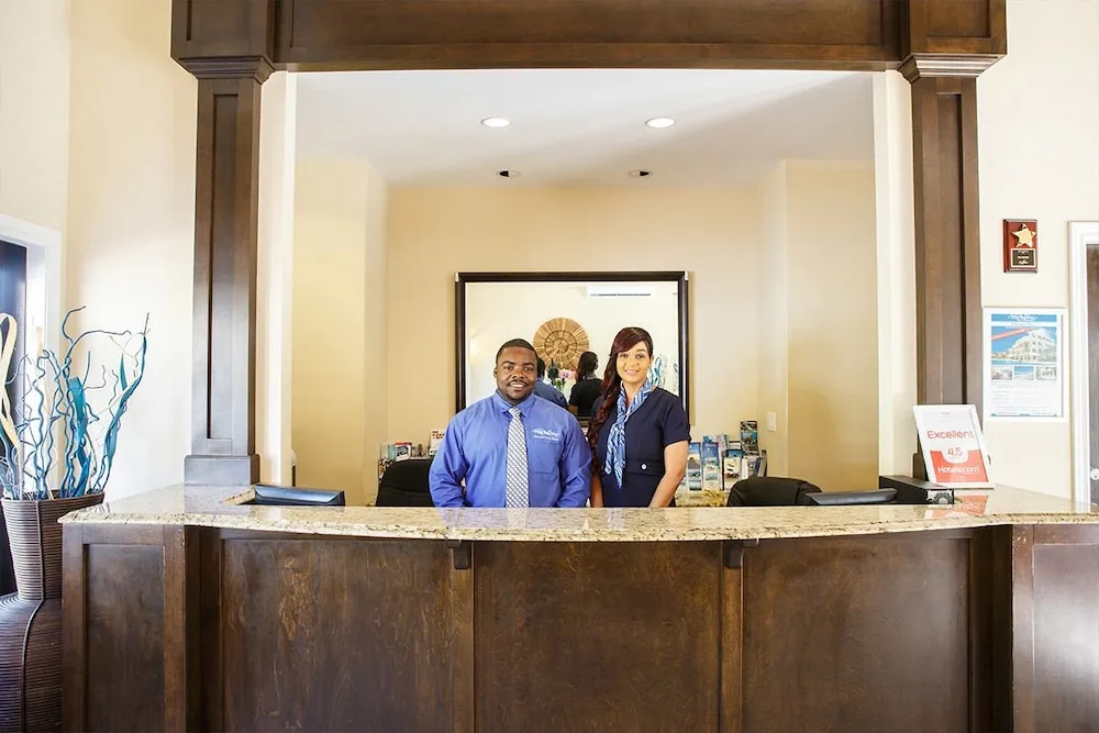 Front desk with two uniformed staff members behind the counter at Villa del Mar.