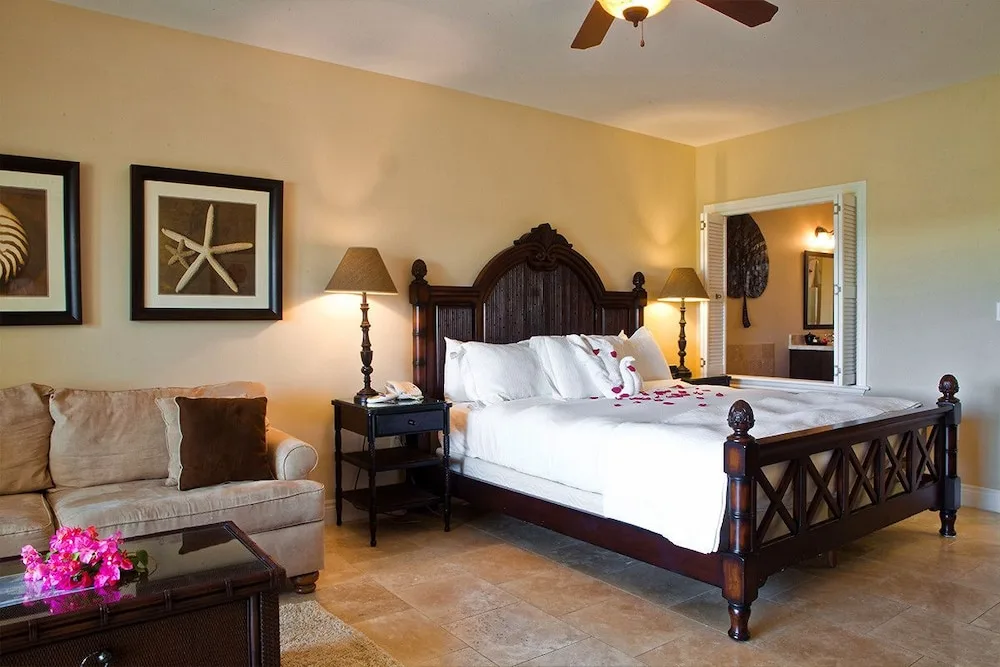 Guest room with dark wood king bed, sofa and shell artwork at Villa del Mar.