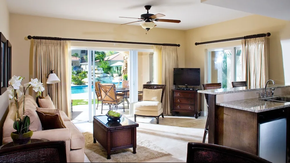 Living area with sofa, kitchenette, TV, and patio view at Villa del Mar.