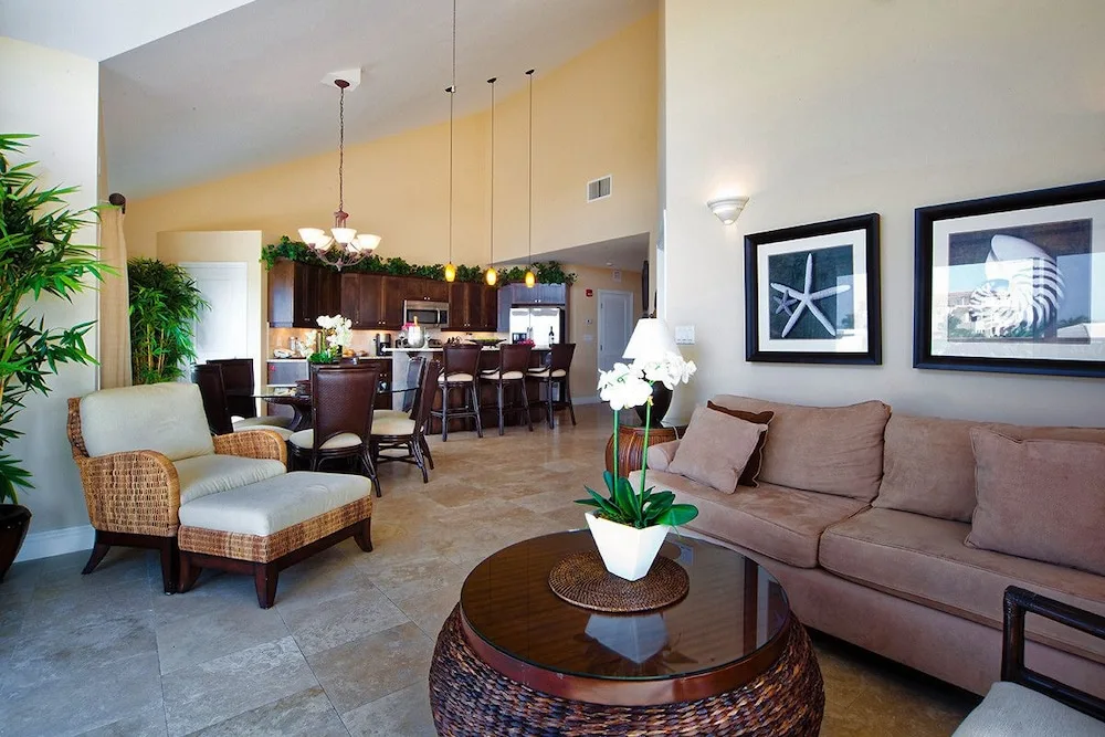 Living and dining area with sofa, round table, and kitchen beyond at Villa del Mar.