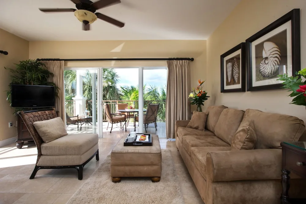 Living room with sofa, chaise, TV, and balcony doors at Villa del Mar.