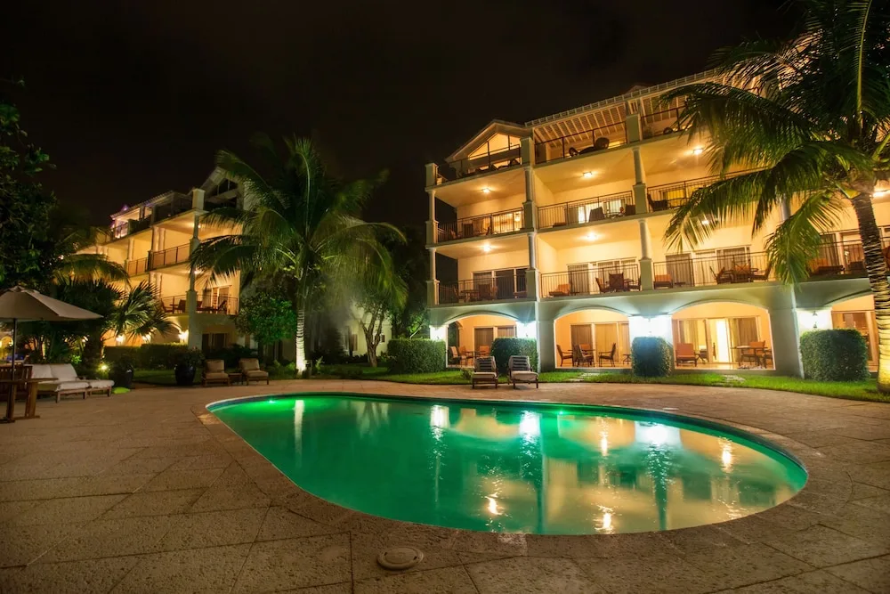 Nighttime pool scene with lit resort buildings and palms at Villa del Mar.