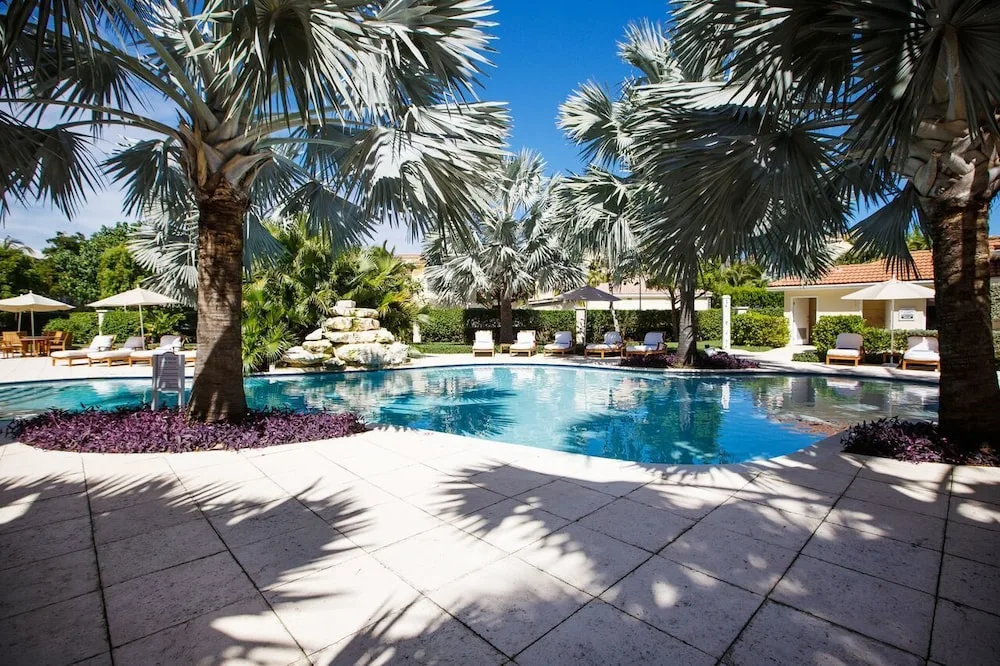 Resort pool with palm trees, loungers, umbrellas, and blue water at Villa del Mar.