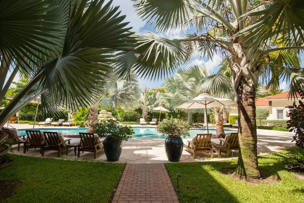 Palm-lined pool courtyard with loungers and umbrellas at Villa del Mar.