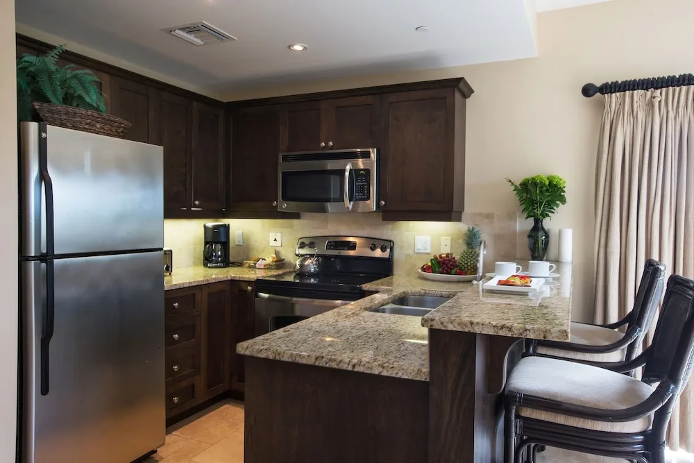 Suite kitchen with granite bar, appliances, and stools at Villa del Mar.