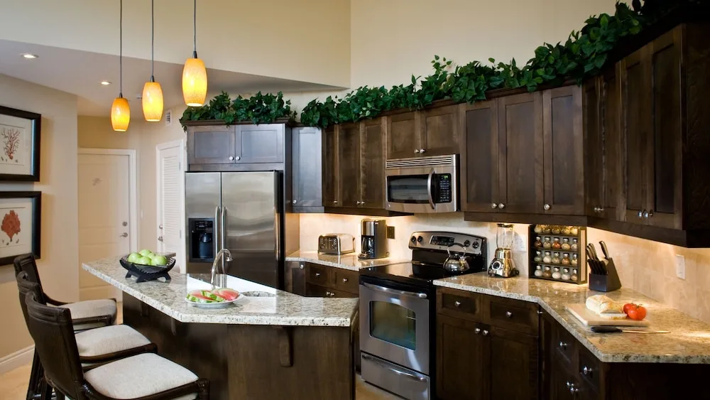 Suite kitchen with island seating, dark cabinets, and pendant lights at Villa del Mar.